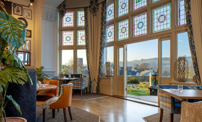 Tables in a restaurant with large doors leading out toward views of the countryside
